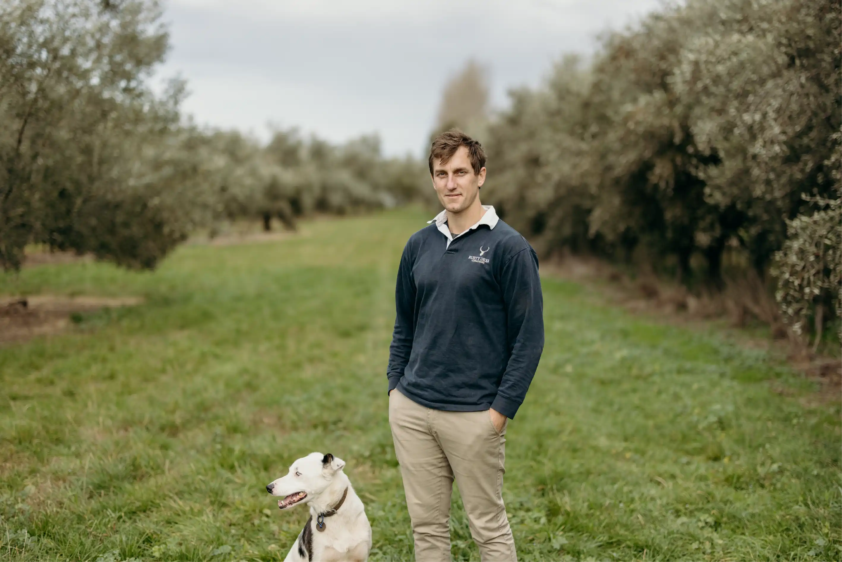 Tim Groves, founder of NZ Shopify agency Blank Slate Co., standing in an olive grove with his dog